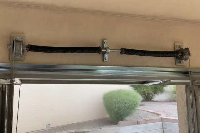 Torsion springs and cable drums on a garage door shaft during maintenance in Phoenix, AZ.