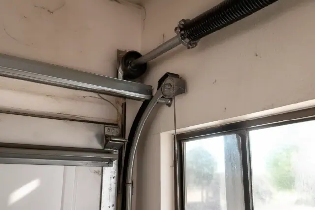 New steel cable and tensioned torsion spring on a garage door track in a Phoenix, AZ home garage.