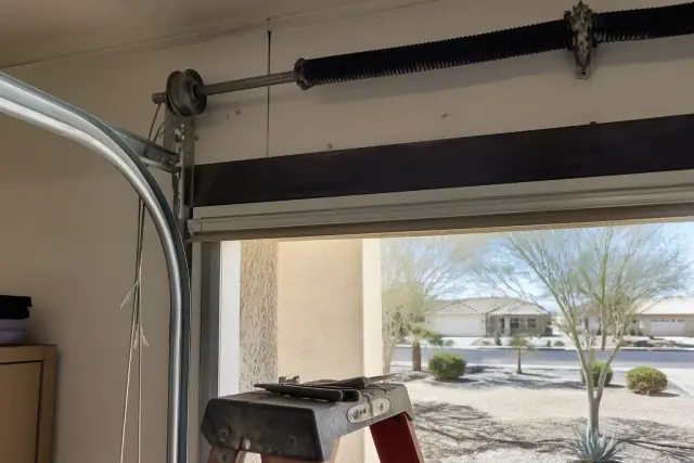 Technician repairing frayed garage door cables near the tracks at a home in Phoenix, AZ.