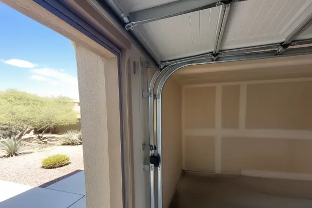 Garage door rollers, tracks, and cables installed on a stucco home exterior in Phoenix, AZ.