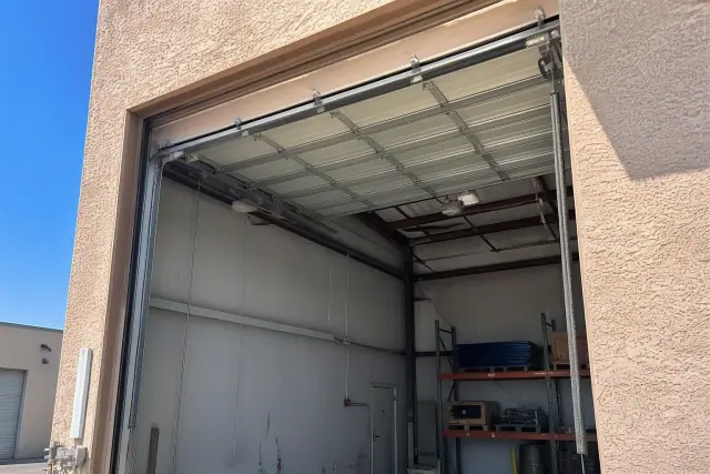 Commercial garage door repair on an industrial warehouse bay in Phoenix, AZ with high-lift tracks and steel springs.