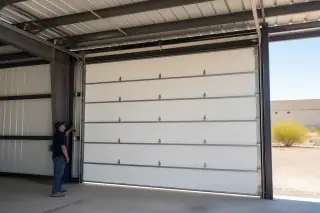 Technician inspecting the alignment of a closed commercial overhead door in a Phoenix, AZ warehouse bay.