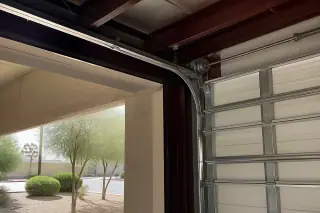 High-lift commercial garage door tracks mounted to a steel ceiling frame at a property in Phoenix, AZ.