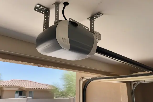 Garage door opener motor mounted to ceiling brackets on a stucco building in Phoenix, AZ.