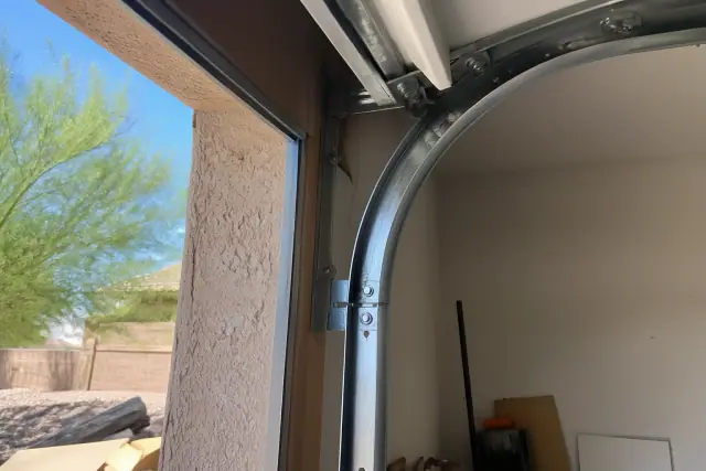 New garage door rollers installed in metal tracks on a stucco wall in Phoenix, AZ.