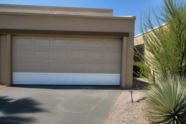 A new garage door panel installed on a home in Phoenix, AZ, with a xeriscaped front yard and asphalt driveway.