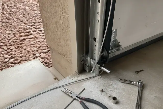 Technician repairing a frayed garage door cable near the bottom bracket in Mesa, AZ.