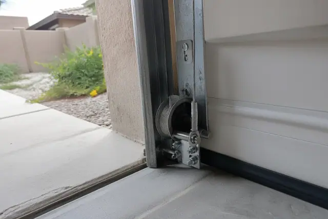 New braided steel cable attached to a garage door bottom bracket at a home in Peoria, AZ.