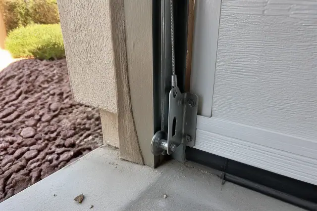 Technician repairing a garage door lifting cable at the bottom bracket of a home in Gilbert, AZ.