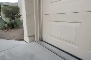 Braided steel lifting cable attached to a garage door corner bracket at a residential home in Phoenix, AZ.