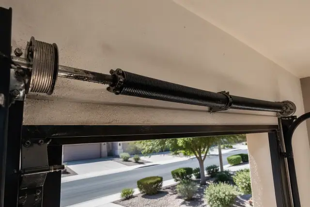 Garage door torsion springs and cable drums with lubricant on a metal shaft at a job site in Gilbert, AZ.