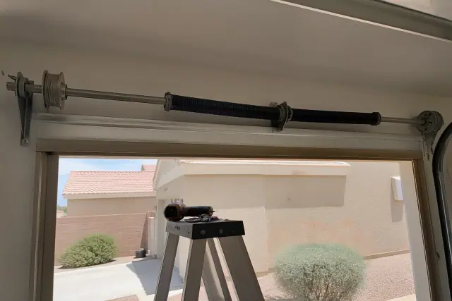 Torsion springs and cable drums on a garage door shaft during maintenance at a home in Glendale, AZ.