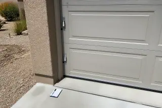 Lubricant on garage door hinges and a maintenance tool on a driveway in Phoenix, AZ.