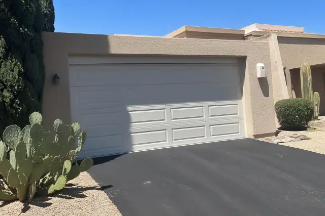 Closed garage door with horizontal panels and desert landscaping on a sunny day in Phoenix, AZ.