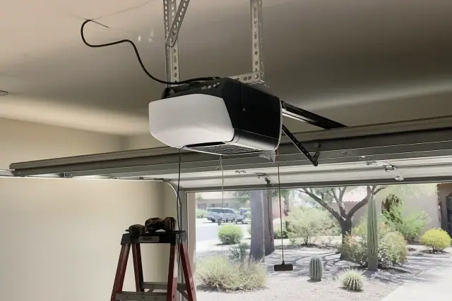 Garage door opener motor installed on a ceiling bracket in a Scottsdale, AZ home with desert landscaping in the background.
