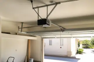 Garage door opener motor and belt drive rail mounted to a ceiling in a Phoenix, AZ garage.