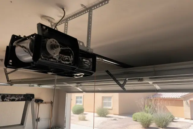 Technician repairing a garage door opener motor and belt drive rail on a home in Glendale, AZ.