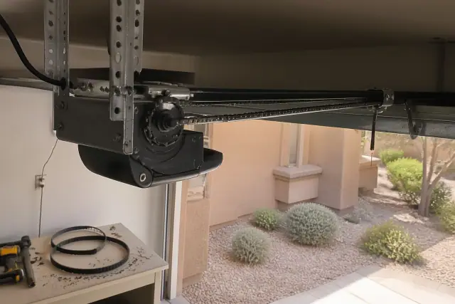 Garage door opener motor mounted to ceiling brackets with a new chain drive in a Gilbert, AZ residential garage.