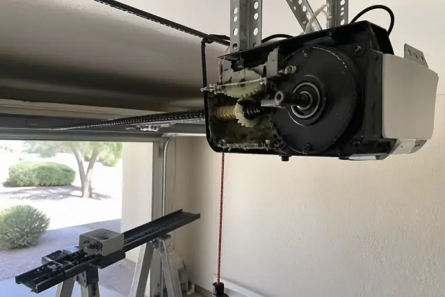 Garage door opener motor repair with a detached drive rail and worn gears at a home in Peoria, AZ.