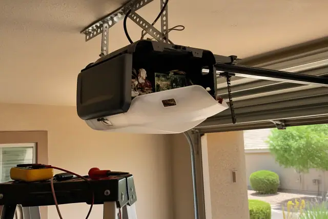 A technician repairing a garage door opener motor assembly inside a garage in Mesa, AZ.