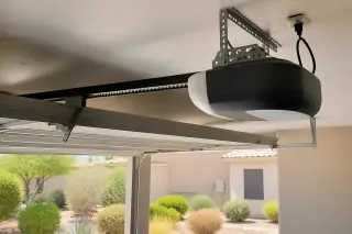 Garage door opener motor and drive rail mounted to the ceiling of a garage in Phoenix, AZ.