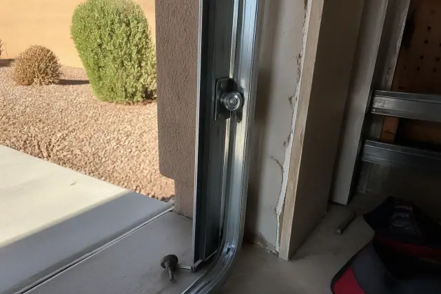 Technician replacing a steel garage door roller in a metal track at a home in Gilbert, AZ.