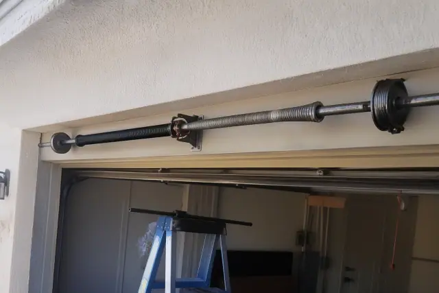 Torsion springs and a winding bar on a ladder during a garage door repair in Avondale, AZ.