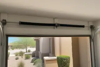 Torsion springs and cable drums mounted on a metal shaft above a garage door in Phoenix, AZ.