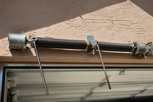 Torsion springs and cable drums on a garage door shaft during maintenance in Phoenix, AZ.