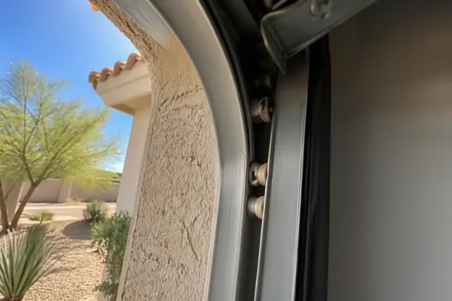 Warped nylon rollers in a heat-distorted metal track on a stucco wall at a jobsite in Phoenix, AZ.