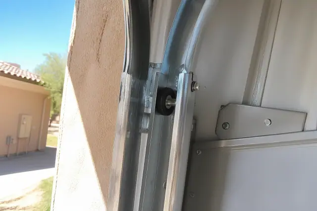 New high-heat rollers installed in an overhead garage door track on a stucco wall in Phoenix, AZ.