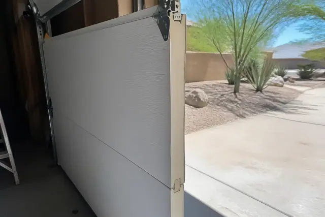 Insulated garage door panel with exposed foam core during installation at a home in Phoenix, AZ.