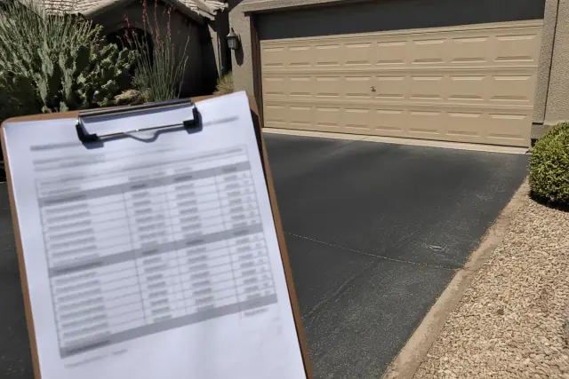Clipboard with an itemized garage door repair estimate in a residential driveway in Phoenix, AZ.
