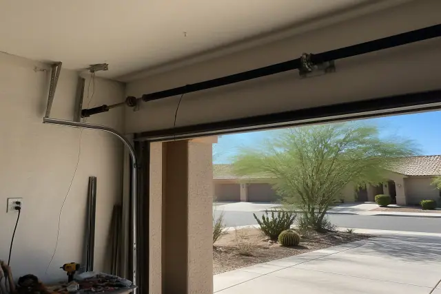 Low-headroom garage door cable repair in a Phoenix, AZ garage with tools and spring assemblies visible.
