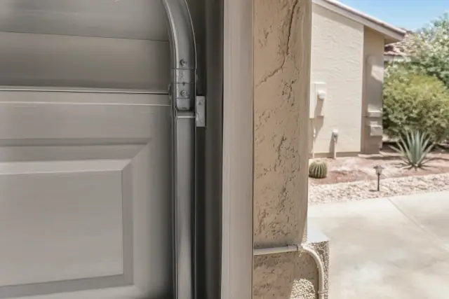 Garage door rollers securely seated in the metal guide tracks during a repair in Phoenix, AZ.