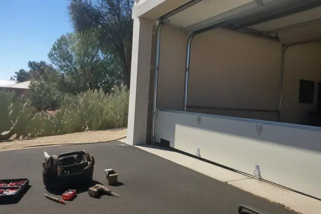 Garage door installation with tools and cacti on a driveway in Phoenix, AZ.