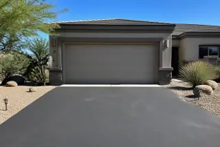 Closed overhead garage door with horizontal panels and desert landscaping at a home in Phoenix, AZ.