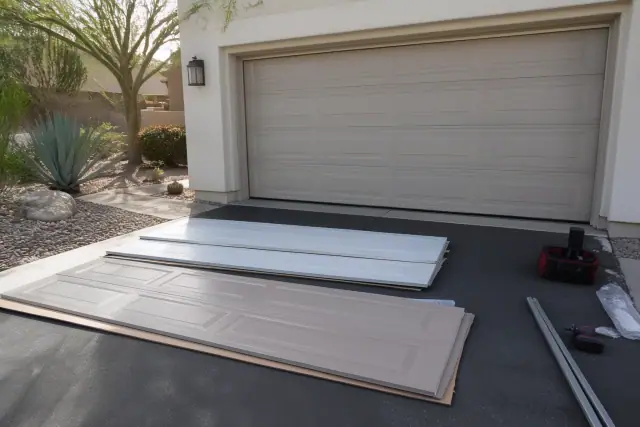 OEM and aftermarket garage door panels being replaced in a residential driveway in Phoenix, AZ.