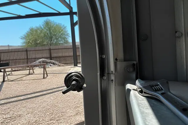 Technician performing an off-track commercial garage door realignment on a metal track system in Phoenix, AZ.