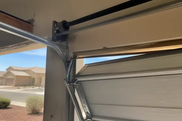 Bent garage door track and dislodged roller on a door panel at a home in Avondale, AZ.