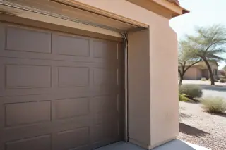 Garage door rollers seated in metal tracks on a stucco home in Phoenix, AZ.
