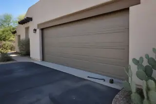 Fixed overhead garage door with a pry bar and laser level on a driveway at a home in Phoenix, AZ.