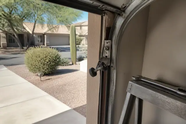 Technician repairing a displaced garage door roller on an overhead track at a home in Phoenix, AZ.