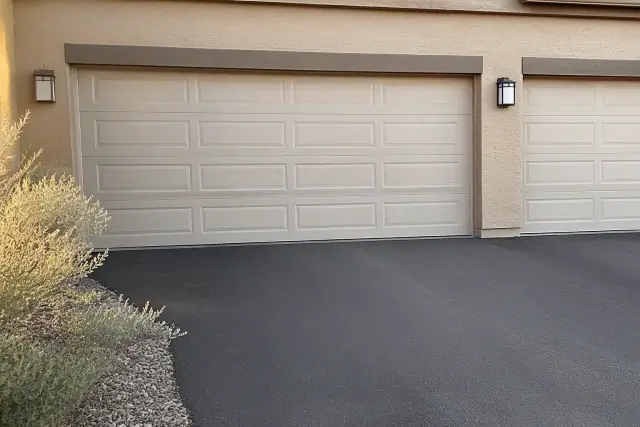 A damaged garage door panel next to undamaged sections on a residential driveway in Phoenix, AZ.