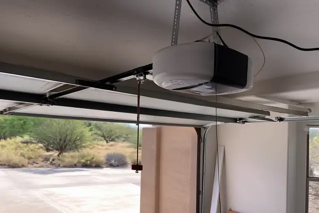 Garage door opener motor mounted to ceiling brackets during a repair job in Phoenix, AZ.