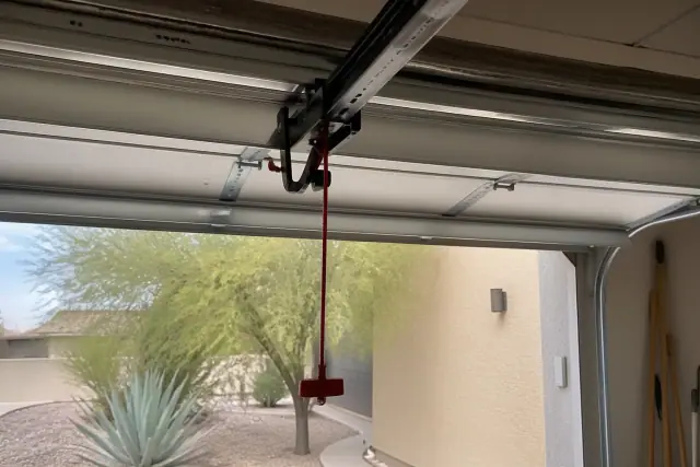 Red emergency release cord and carriage trolley on a garage door in Phoenix, AZ.