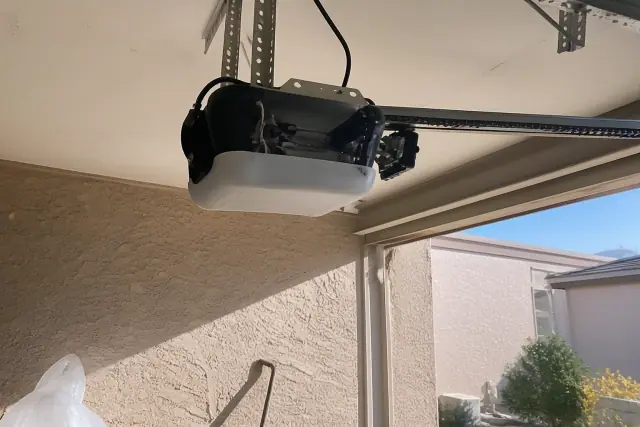 Garage door opener motor mounted to ceiling brackets with a drive rail in a Phoenix, AZ garage.