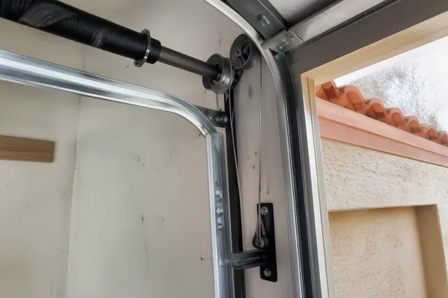 Residential garage door cable repair on a steel pulley system in a Phoenix, AZ home garage.
