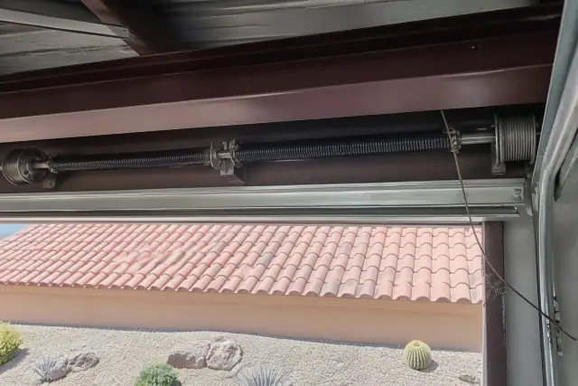 Torsion springs and a frayed lift cable on a commercial garage door track in Phoenix, AZ.