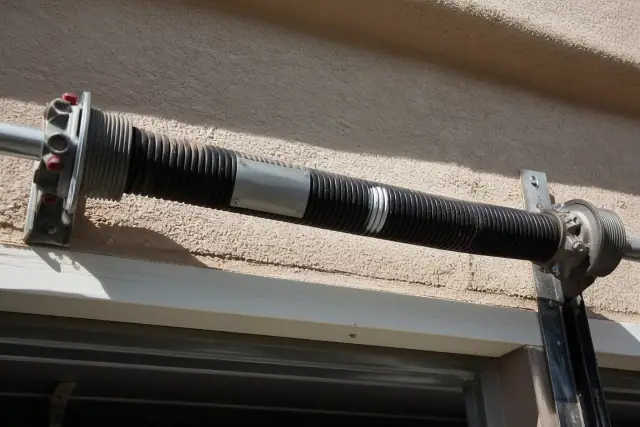 Torsion spring with manufacturer label mounted on a shaft above a garage door in Phoenix, AZ.